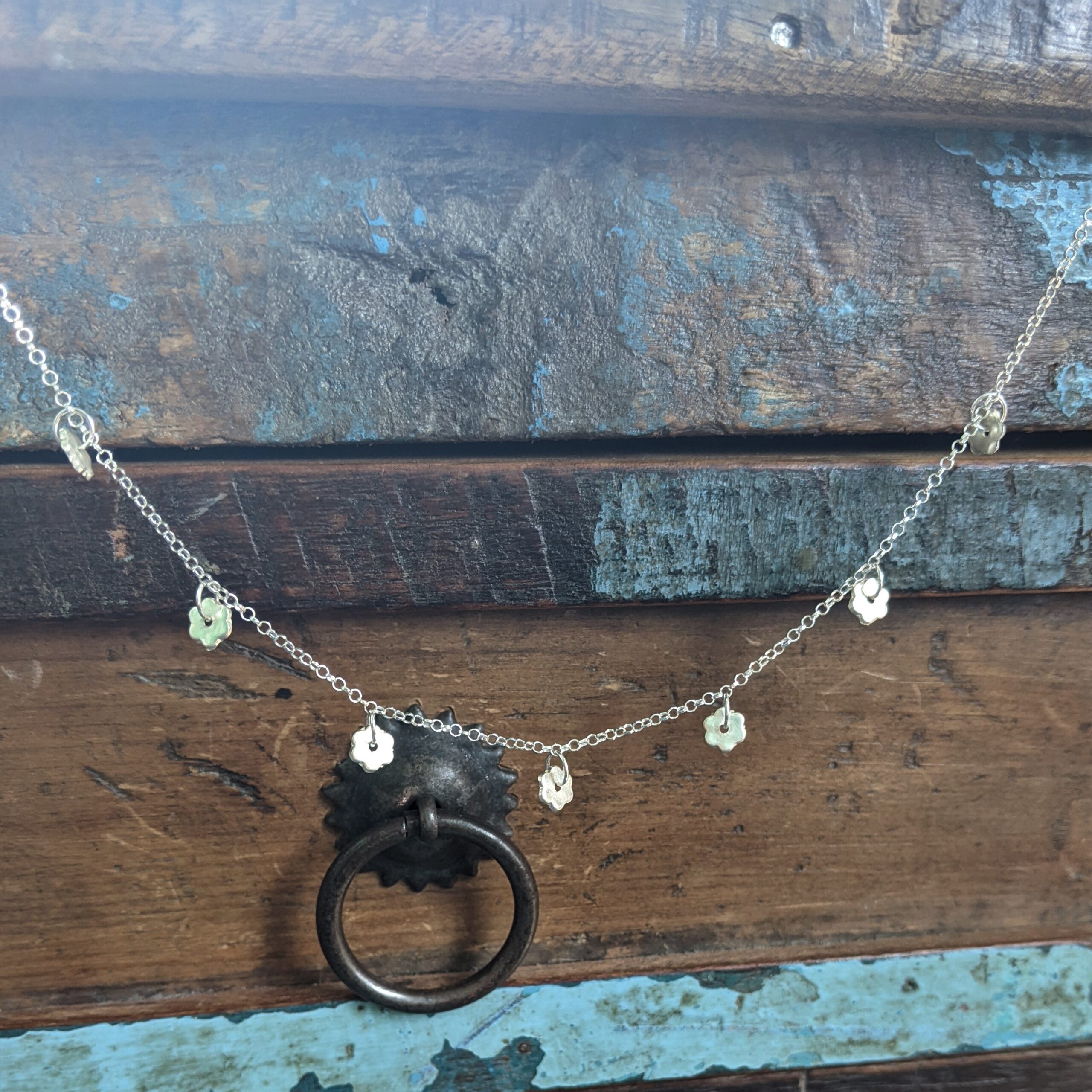 N106 Pamela Necklace. 7 tiny flower, fine silver charms suspended on a recycled sterling silver chain. Comes with extension chain to wear at different lengths.