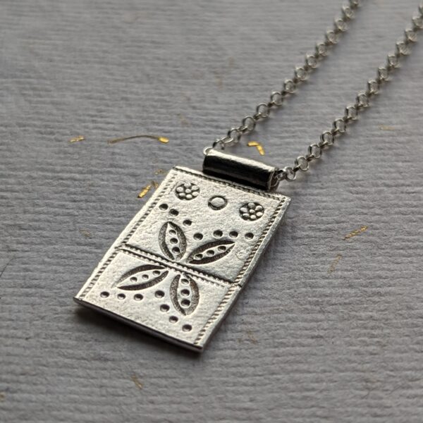N110 Maple Pendant Necklace. A rectangular bold pendant necklace with flower and geometric stamping. Fair Trade, Handmade, REcycled fine silver pendant on a recycled sterling silver chain.