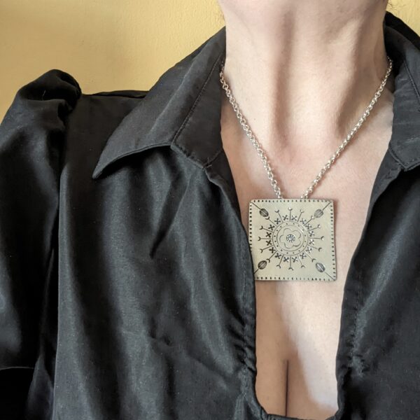 HL746 Ostara Necklace. Fair Trade, handmade from recycled silver this pendant is completed with a handcrafted hill tribe silver chain with a t-bar clasp. The square pendant has oxidised stamped detailing of flowers, leaves and geometric patterns.