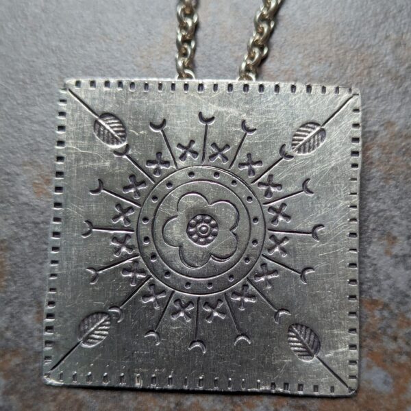 HL746 Ostara Necklace. Fair Trade, handmade from recycled silver this pendant is completed with a handcrafted hill tribe silver chain with a t-bar clasp. The square pendant has oxidised stamped detailing of flowers, leaves and geometric patterns.