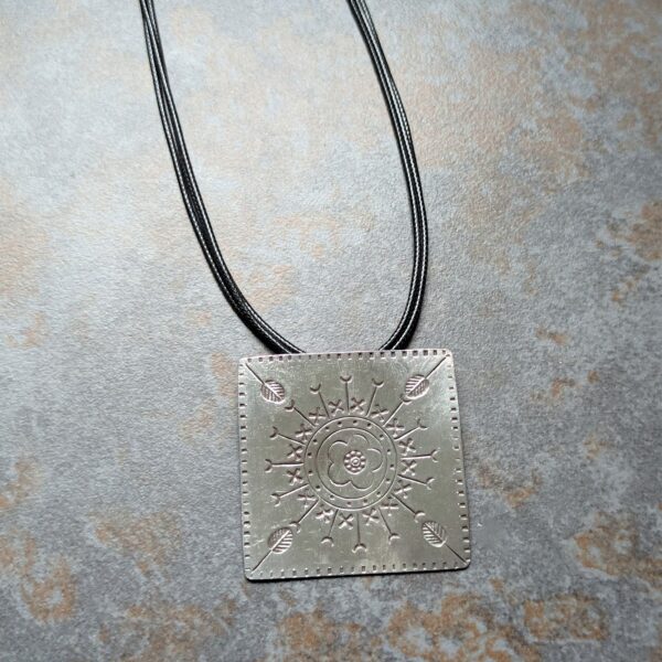 HL747 Ostara Necklace. Fair Trade, handmade from recycled silver this pendant can be strung on either a tough nylon cord or a snake chain. The square pendant has oxidised stamped detailing of flowers, leaves and geometric patterns.