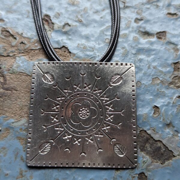 HL747 Ostara Necklace. Fair Trade, handmade from recycled silver this pendant can be strung on either a tough nylon cord or a snake chain. The square pendant has oxidised stamped detailing of flowers, leaves and geometric patterns.