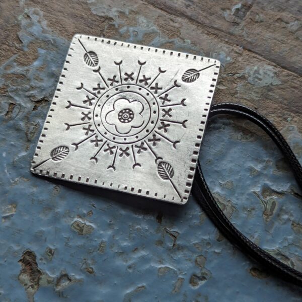 HL747 Ostara Necklace. Fair Trade, handmade from recycled silver this pendant can be strung on either a tough nylon cord or a snake chain. The square pendant has oxidised stamped detailing of flowers, leaves and geometric patterns.