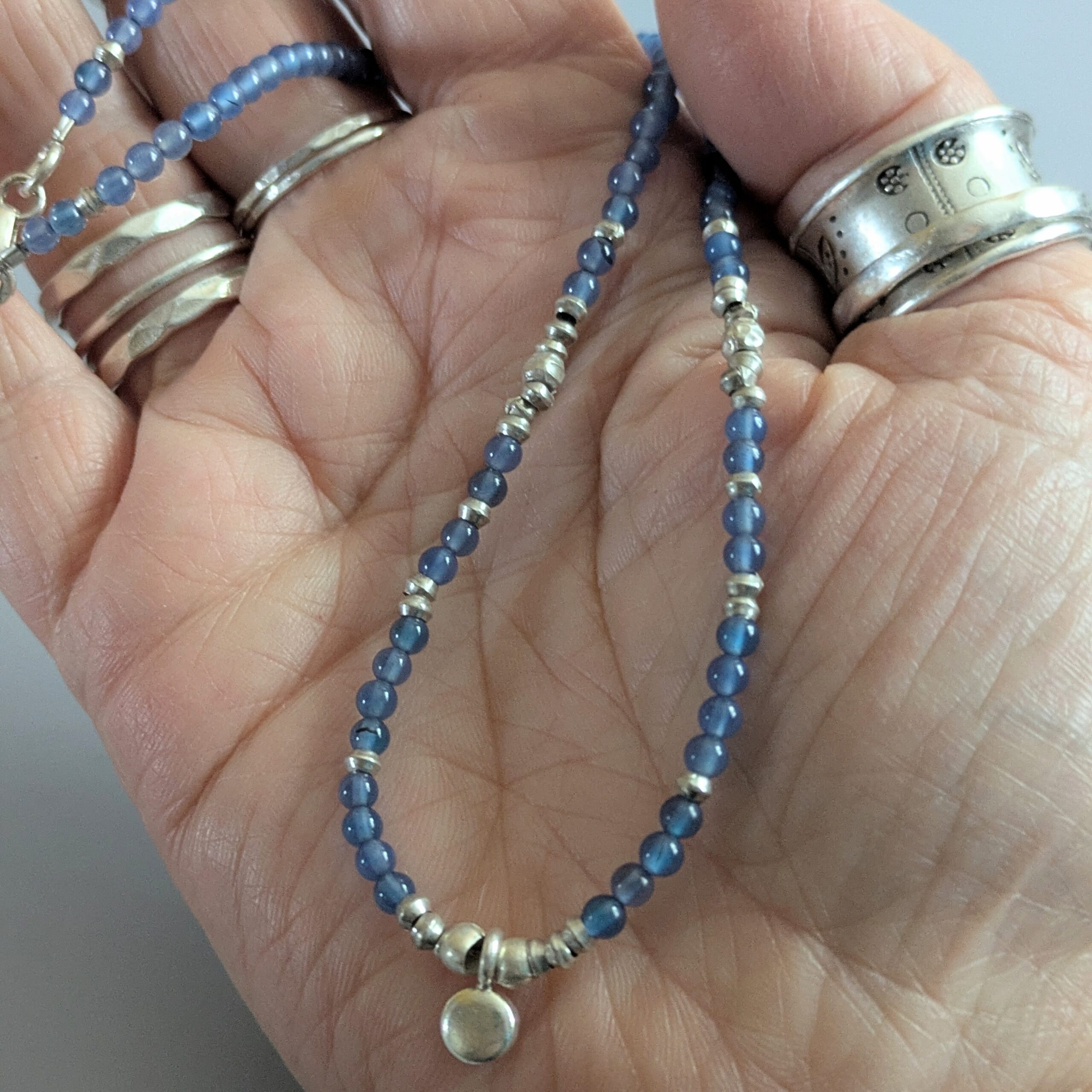 N125 Doris Gem and Charm Necklace - Blue Aventurine. Faceted gemstone beads with Fair Trade silver beads and a central silver charm detail. Clasp sterling silver.